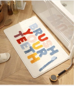 Detail view of white non-slip bath mat with colorful Brush Your Teeth lettering on wood floor