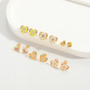 Collection of colorful enamel heart earrings with gold plating on a white display stand