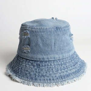 Detailed view of light blue denim bucket hat with frayed edges and distressed ripped holes