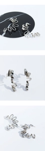 Macro details of silver wavy ribbon earrings showing mirror polished metal and artistic folds