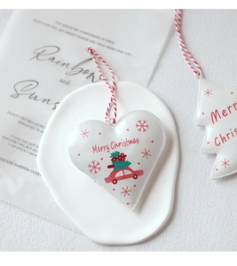 Close-up of white metal Christmas ornaments with tree and car motifs on ceramic plate