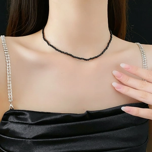 Close-up of a minimalist black crystal beaded necklace worn on a model's neck