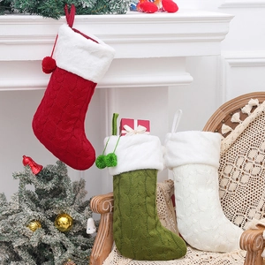 Three knit Christmas stockings in red, green, and white with plush cuffs and pom-poms