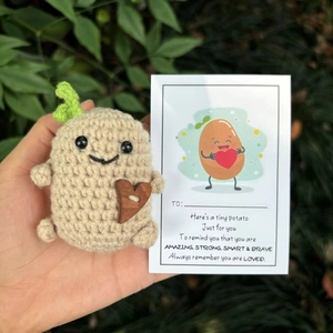 Nahaufnahme einer handgehäkelten Kartoffel-Puppe mit Herzknopf und Motivationskarte