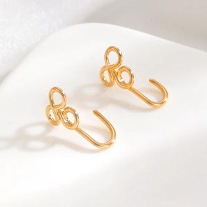 Gros plan sur des boucles d'oreilles grimpantes dorées sur support en céramique blanche
