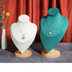 Detail of wooden necklace display stands in white fabric and green velvet textures