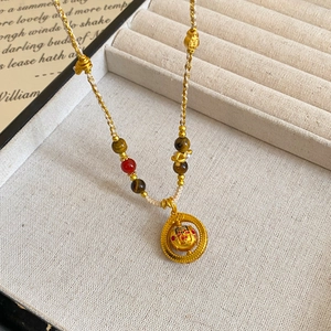 Detail of a Chinese-style gold pendant necklace with woven cord and gemstone beads