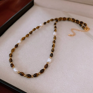 Détail d'un collier en perles d'eau douce et œil de tigre avec fermoir mousqueton doré