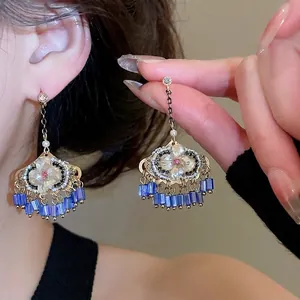 Boucles d'oreilles bohèmes chic à pompons bleus avec design floral blanc et strass