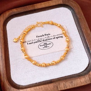 Vue macro d'un bracelet en perles plaqué or 24 carats avec breloque cœur sur bois