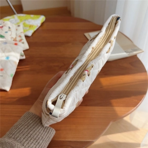 Detailed close-up of a quilted cotton makeup bag with cute bear print on a wooden desk