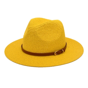 Detail of a bright yellow woven straw Fedora hat featuring a brown belt with a gold buckle