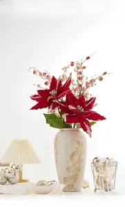 Détail d'un arrangement de poinsettias rouges avec vase en céramique à taches dorées