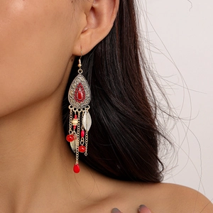 Détail de boucles d'oreilles bohèmes vintage avec perles rouges et accents de feuilles