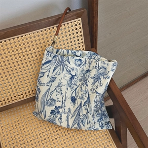 Detail of floral canvas tote bag with blue porcelain pattern on a vintage wicker chair