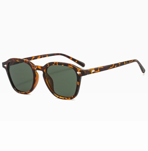Dettaglio occhiali da sole tartarugati con rivetti metallici e lenti verde scuro