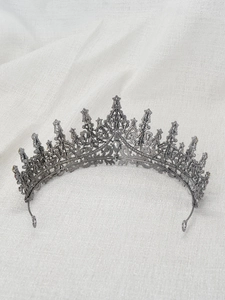 Detailed close-up of an ornate metal princess crown with colorful gems on white linen