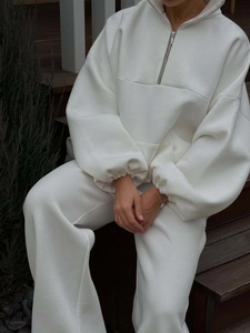 Detail view of white oversize half-zip sweatshirt set with high-quality drape on stairs