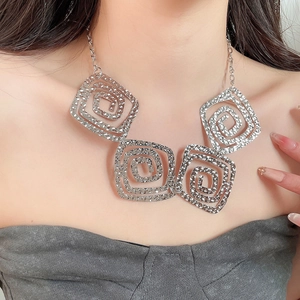 Macro detail of silver square pendants with spiral texture on a delicate chain necklace