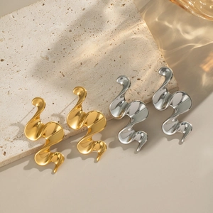 Polished geometric spiral earrings in gold and silver finish on a stone background