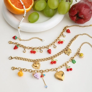 Detailed shot of 18K gold stainless steel bracelets with mixed fruit charms and pearls