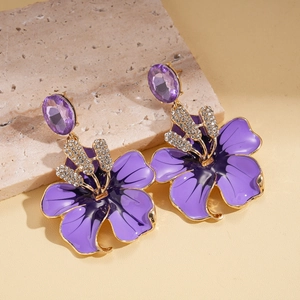 Detail of purple enamel flower earring with rhinestones on natural stone