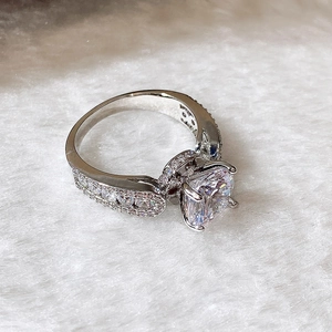Close-up of classic six-prong round zircon engagement ring with pave-set side stones