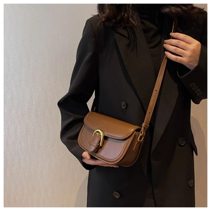 Detailed close-up of dark brown leather saddle bag featuring a gold D-ring buckle hardware