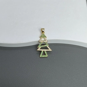 Macro shot of gold Christmas tree pendant with green micro-zircon stones and enamel