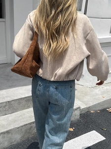 Street style view of light brown long-sleeve jacket and quilted crossbody bag