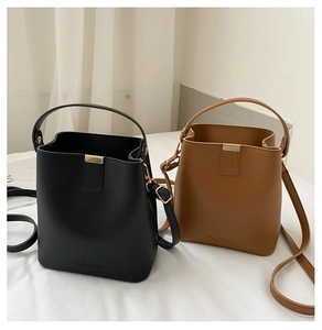Detail minimalistischer Bucket-Bags aus PU-Leder in Schwarz und Braun mit Gold-Schriftzug
