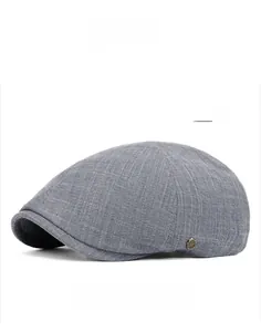 Détail de la texture du tissu de la casquette plate grise et de l'emblème en métal