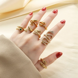Détail de bagues serpent vintage dorées avec pierres vertes et zircons sur la main