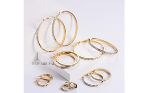 Macro detail of gold hoop earrings set with rhinestones in six various sizes