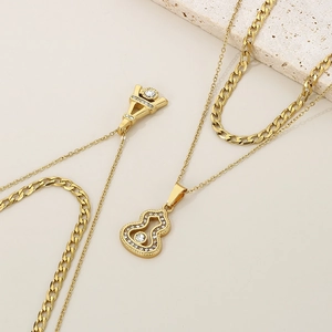 Detail view of double-layered gold necklaces with Eiffel Tower and gourd pendants