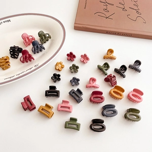 Set of mini Morandi hair claws in square and flower shapes on a white ceramic plate