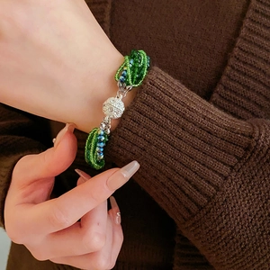 Gros plan d'un bracelet multicouche en perles vertes avec un fermoir magnétique brillant