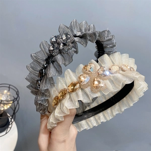 Detail of ruffled headbands with sparkling crystals in beige and grey satin fabric