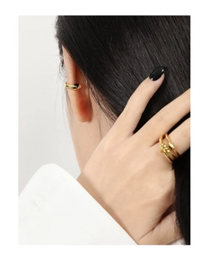Dettaglio di un ear cuff dorato e anello a nodo con design geometrico lucido