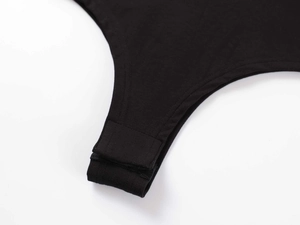 Detailed close-up of the adjustable snap button closure on a black cotton bodysuit
