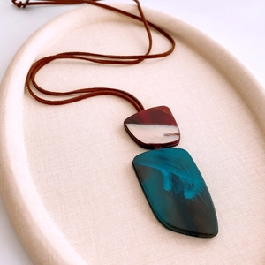 Detail of artistic resin pendant with irregular geometric layers on a leather cord