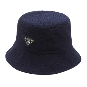 Navy blue bucket hat with textured fabric and a metal triangle fashion badge on front
