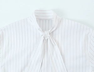 Detail of pussy-bow neckline on white and brown striped shirt with button fastener