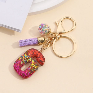 Detail of resin number 6 keychain with colorful sequins, star globe and purple tassel