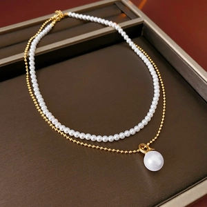 Detail of layered gold beaded chain with elegant faux pearls on a brown tray