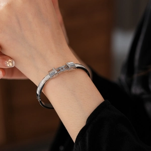 Close-up of a silver titanium steel T-shaped bangle with zircon inlay on a model wrist