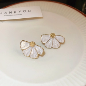 Détail de boucles d'oreilles fleurs aux pétales blancs et centre doré sur une assiette