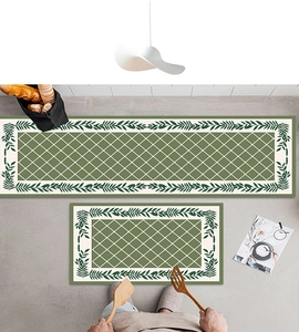 Detail of 2-piece green kitchen mat set with leaf borders on a grey floor