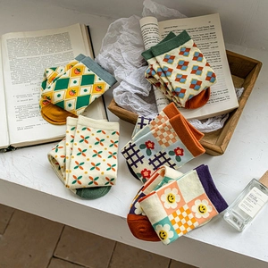 Vintage cotton crew socks with argyle and floral patterns on a rustic wooden tray