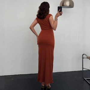 Detail view of the sleek brick red sleeveless bodycon maxi dress from a side profile